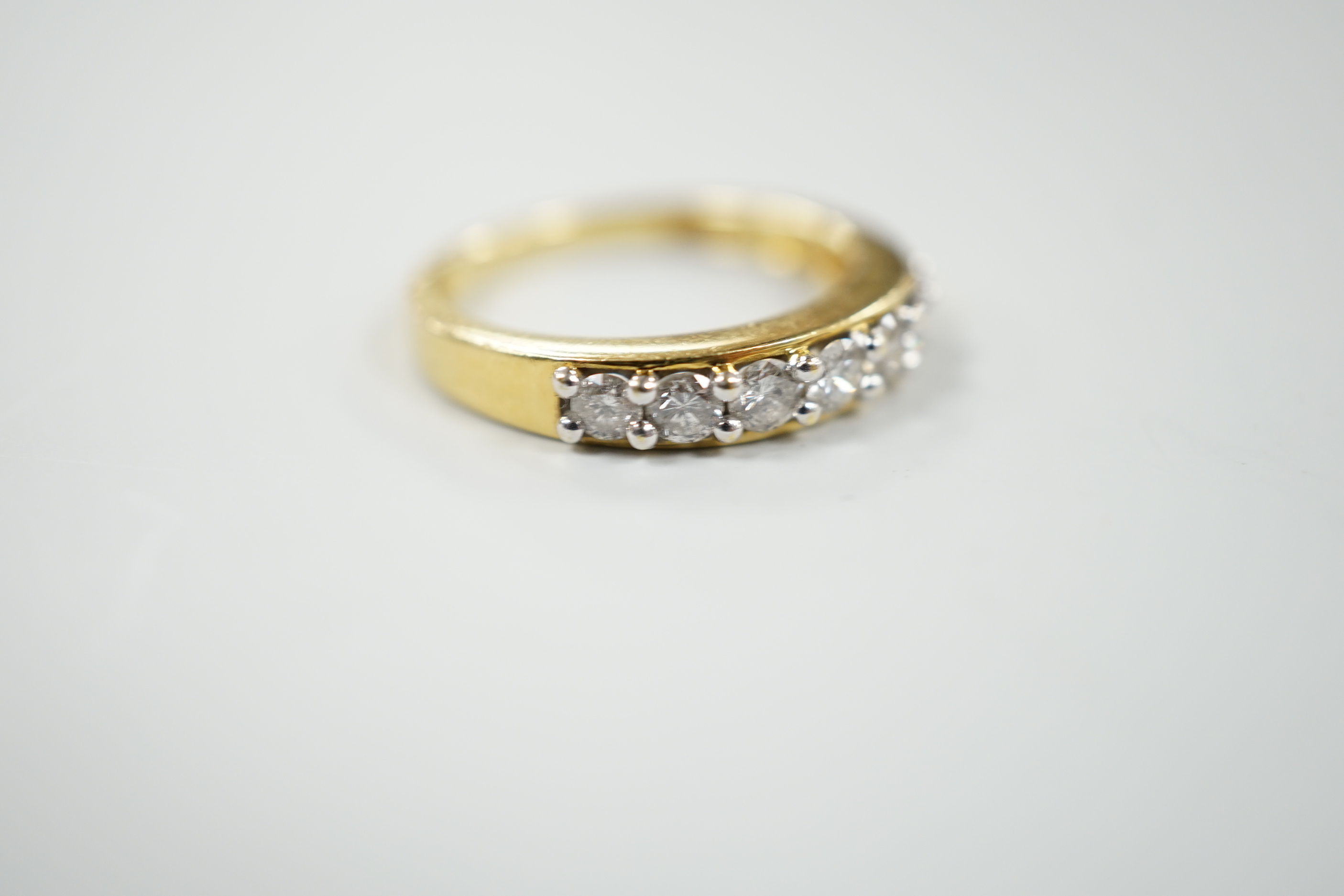 A modern 18ct gold and seven stone diamond set half hoop ring, total carat weight 0.50ct, size J, gross weight 3.4 grams.